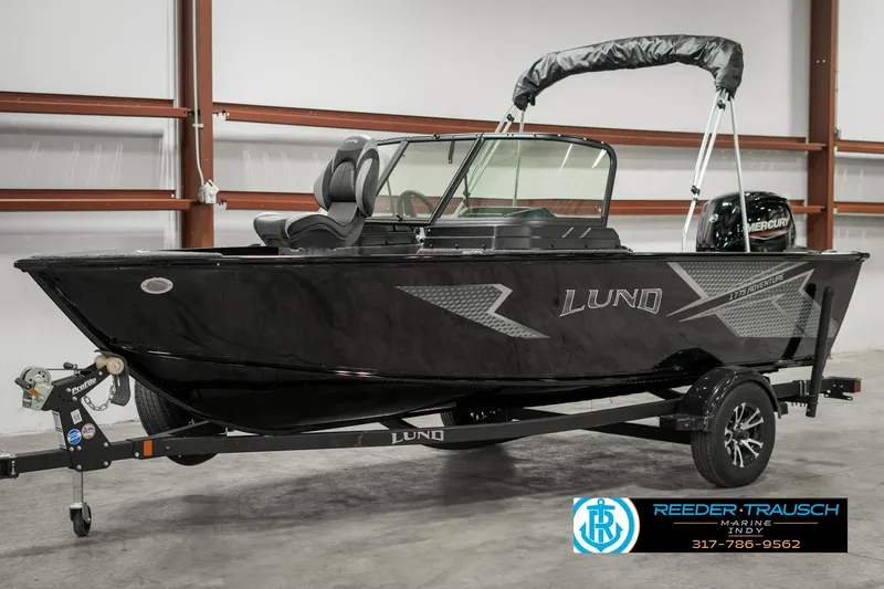 Slide: The Image of 2025 Lund 1775 Adventure Sport boat in showroom, black exterior, on trailer. - 2