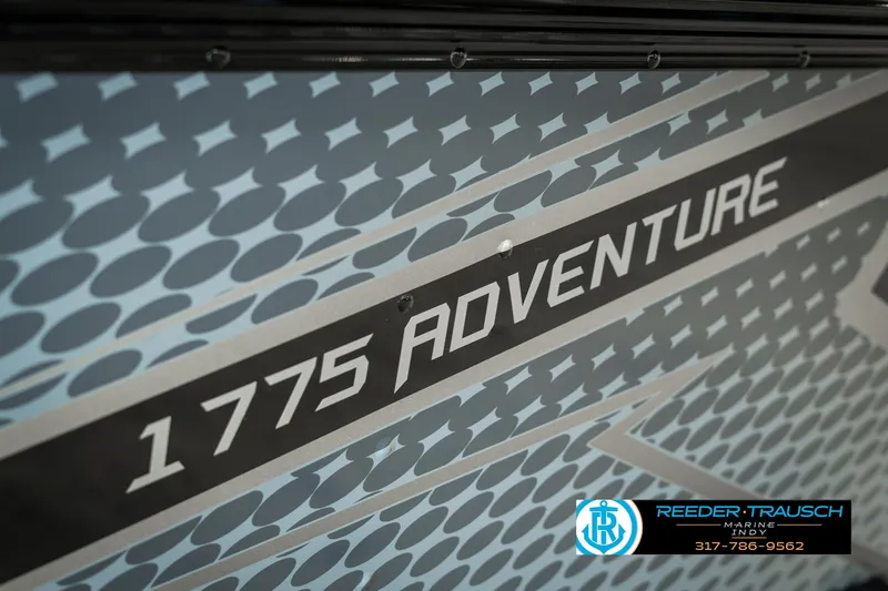 Slide: The Image of 2025 Lund 1775 Adventure Sport boat with patterned design and Reeder-Trausch Marine logo. - 45