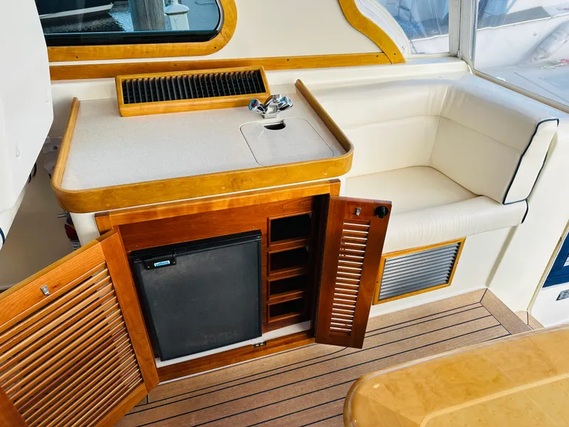 Slide: The Image of 2009 Sabre 42 Hardtop Express interior with wood cabinetry, mini fridge, and cushioned seating. - 17