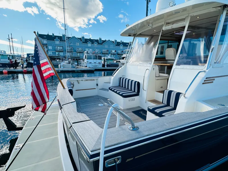 Slide: The Image of 2009 Sabre 42 Hardtop Express yacht docked, featuring striped seating and American flag. - 2