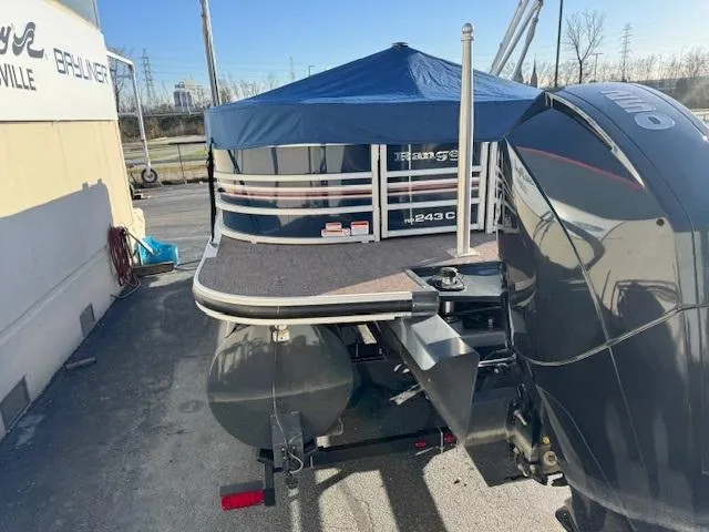 Slide: The Image of 2021 Ranger RP243C pontoon boat with blue canopy and powerful outboard motor. - 13