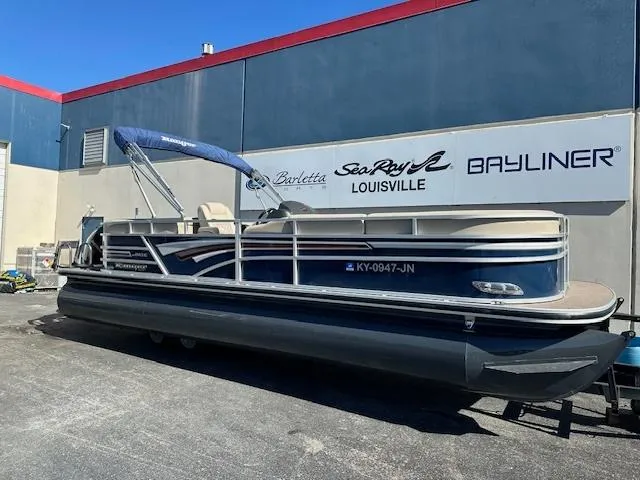 Slide: The Image of 2021 Ranger RP243C pontoon boat parked outside dealership. - 2
