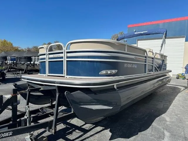 Slide: The Image of 2021 Ranger RP243C pontoon boat on trailer, blue and beige, parked outdoors. - 3