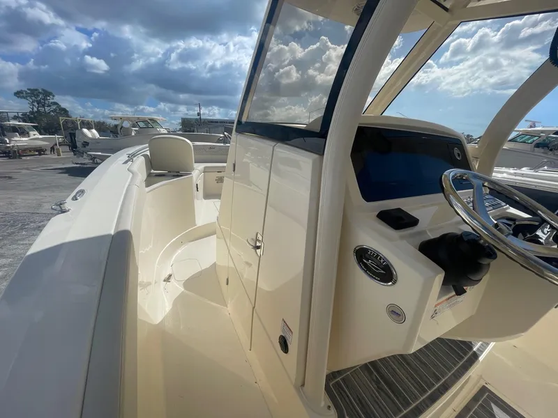 Slide: The Image of 2025 Scout 277 LXF boat interior with steering wheel and dashboard under a cloudy sky. - 4