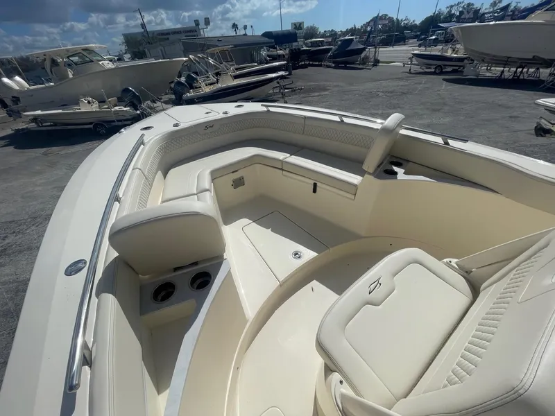 Slide: The Image of 2025 Scout 277 LXF boat interior with seating and cup holders in a sunny marina. - 5