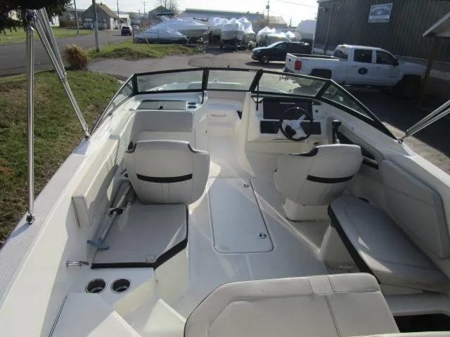 Slide: The Image of 2021 Sea Ray 210 SPX boat interior with seating and steering wheel, parked outdoors. - 4