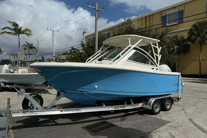 Slide: The Image of 2025 Sailfish 245 DC boat on trailer, blue hull, parked outdoors. - 0