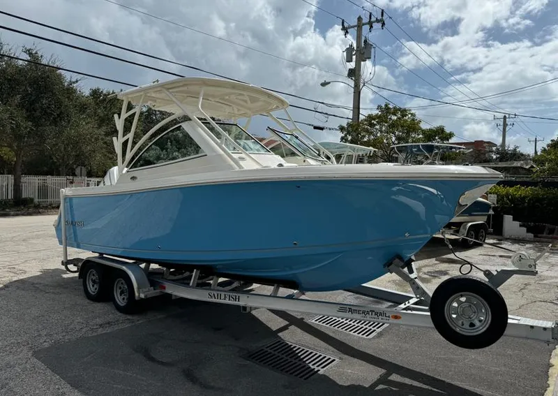 Slide: The Image of 2025 Sailfish 245 DC boat on trailer, blue hull, parked outdoors. - 1