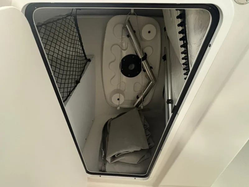 Slide: The Image of Storage compartment in 2025 Sailfish 245 DC boat with netting and folded items. - 10