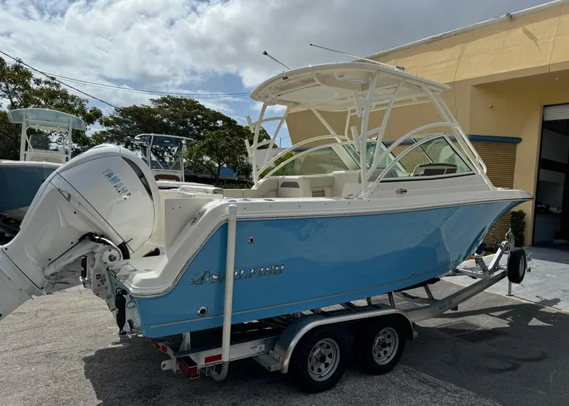 Slide: The Image of 2025 Sailfish 245 DC boat on trailer, blue hull, parked outdoors. - 2