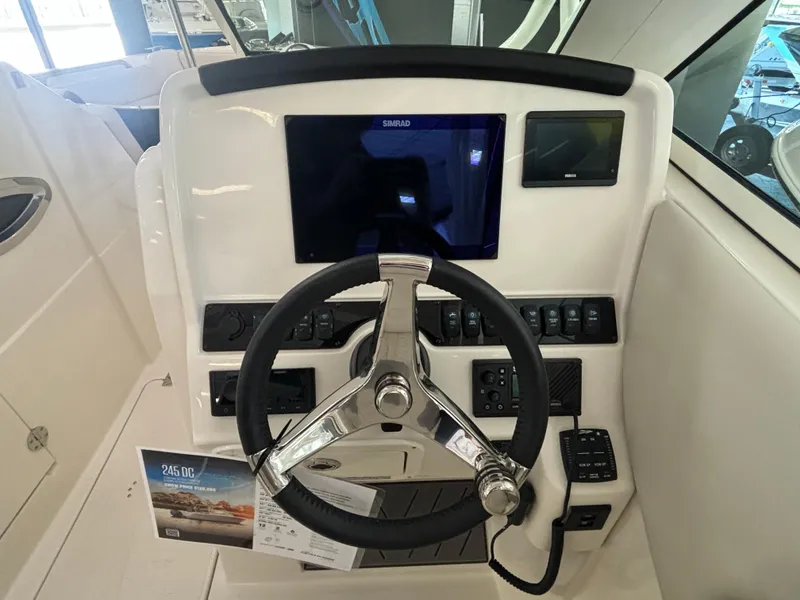 Slide: The Image of 2025 Sailfish 245 DC boat dashboard with steering wheel and navigation controls. - 7