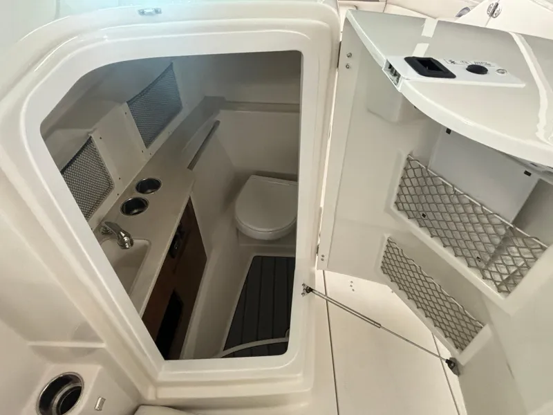 Slide: The Image of Interior of 2025 Sailfish 245 DC boat, featuring compact bathroom with sink and toilet. - 8