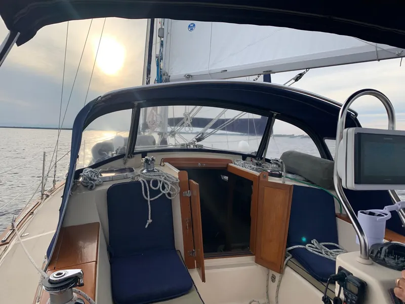 Slide: The Image of 1997 Island Packet 350 sailboat cockpit with blue cushions, sailing at sunset. - 11