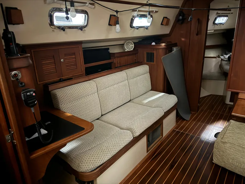 Slide: The Image of Interior of 1997 Island Packet 350 sailboat with wooden flooring and cushioned seating. - 17