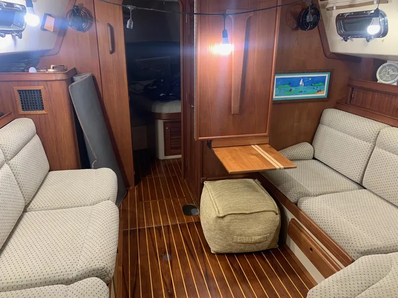 Slide: The Image of Cozy interior of 1997 Island Packet 350 sailboat with wooden flooring and cushioned seating. - 18
