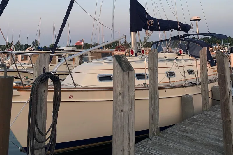 Slide: The Image of 1997 Island Packet 350 sailboat docked at marina, surrounded by wooden posts. - 2