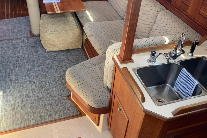 Slide: The Image of Interior of 1997 Island Packet 350 sailboat with cozy seating and compact kitchen area. - 20