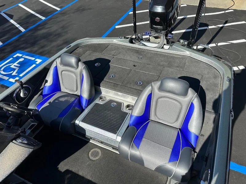 Slide: The Image of 2017 Ranger Z518 boat interior with blue and gray seats in a parking lot. - 17