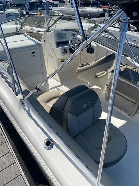 Slide: The Image of 2022 Key West 239 DFS boat interior with seating and dashboard, docked at marina. - 4