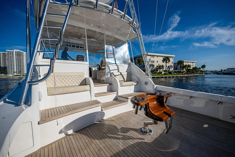 Slide: The Image of 2023 Viking 54 Open yacht deck with seating and fishing chair, docked by waterfront buildings. - 16