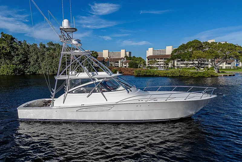 Slide: The Image of 2023 Viking 54 Open yacht on a serene waterway, surrounded by lush greenery. - 2