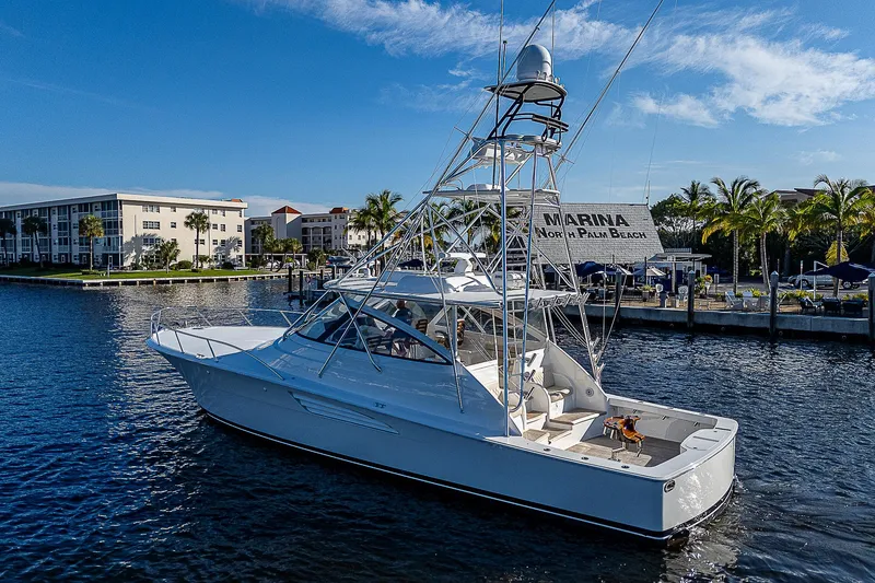 Slide: The Image of 2023 Viking 54 Open yacht docked in a marina, surrounded by calm waters and palm trees. - 6
