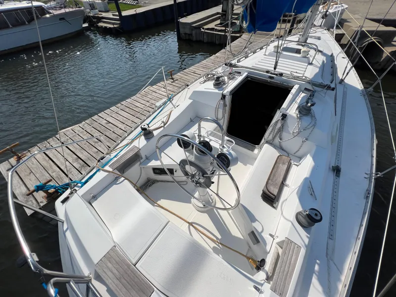 Slide: The Image of 1986 Hunter 31 sailboat docked, featuring spacious cockpit and dual steering wheels. - 16