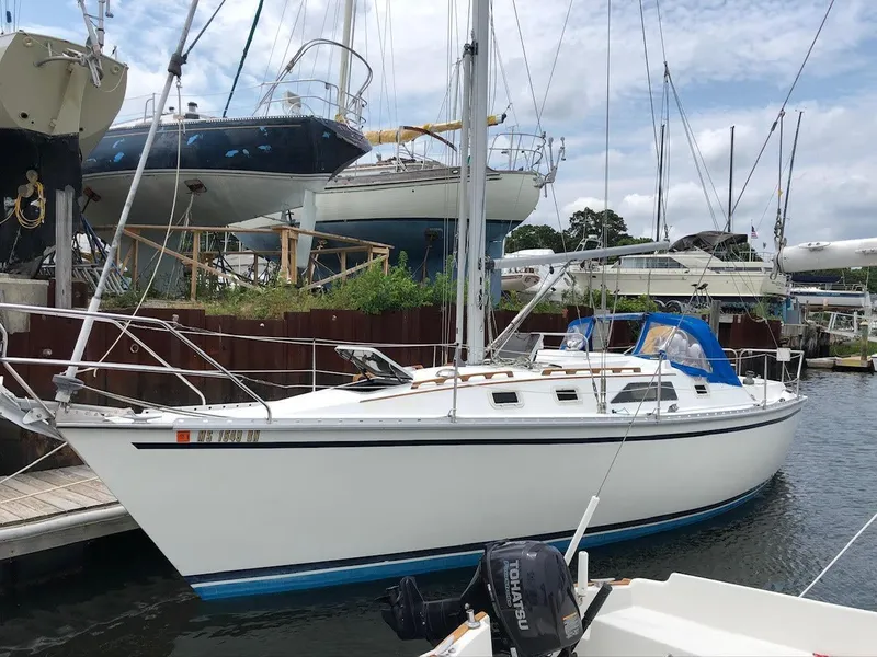Slide: The Image of 1986 Hunter 31 sailboat docked at marina, surrounded by other boats. - 2