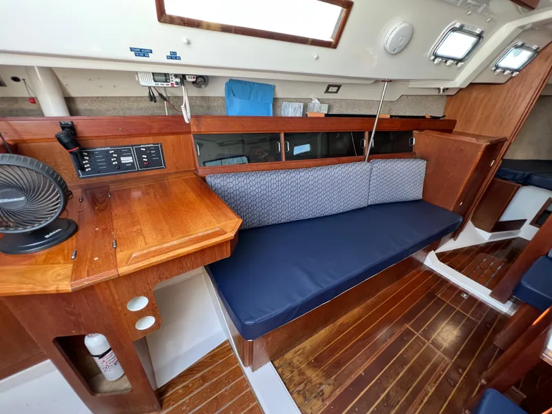 Slide: The Image of Interior of a 1986 Hunter 31 sailboat with wooden furnishings and blue seating. - 26