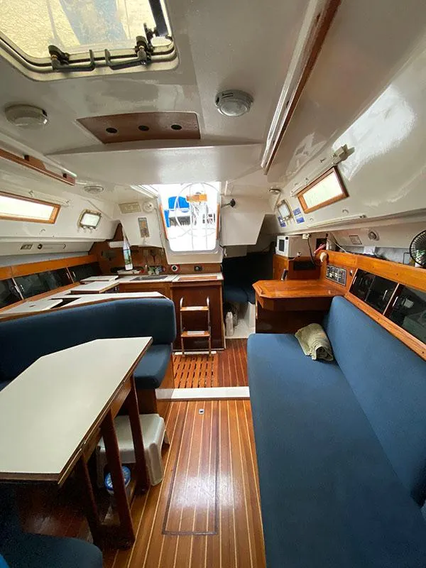 Slide: The Image of Interior of 1986 Hunter 31 sailboat with blue seating and wooden flooring. - 32