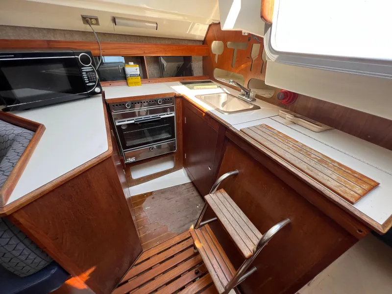 Slide: The Image of 1986 Hunter 31 sailboat kitchen with stove, sink, and wooden cabinetry. - 33