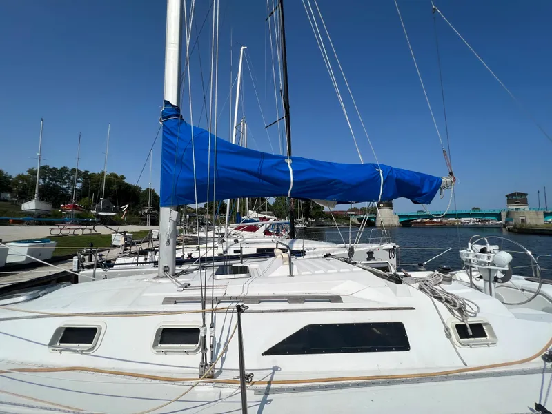 Slide: The Image of 1986 Hunter 31 sailboat docked, blue sail cover, clear sky, marina background. - 8