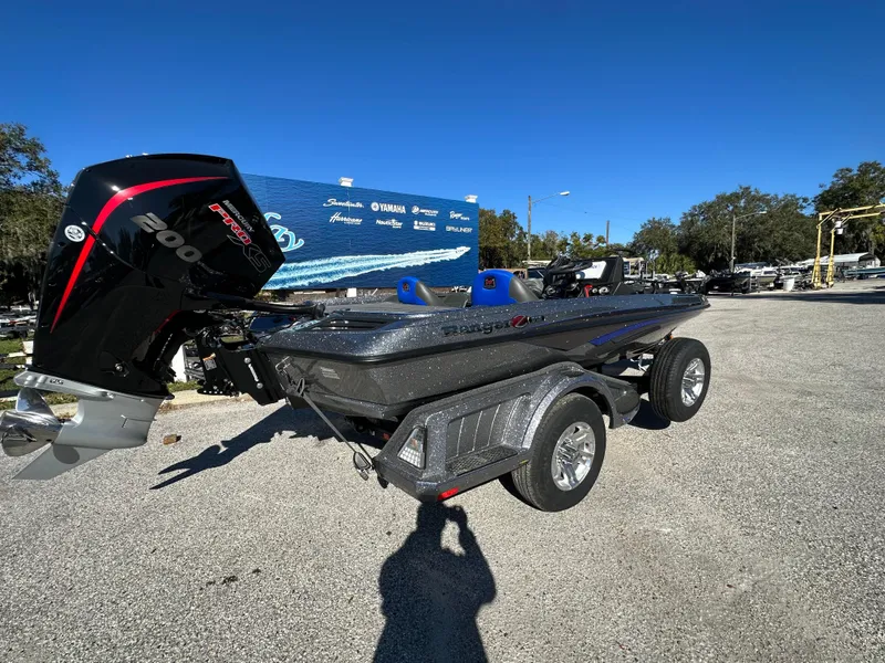 Slide: The Image of 2024 Ranger 518 Cup boat on trailer, parked outdoors under clear blue sky. - 2