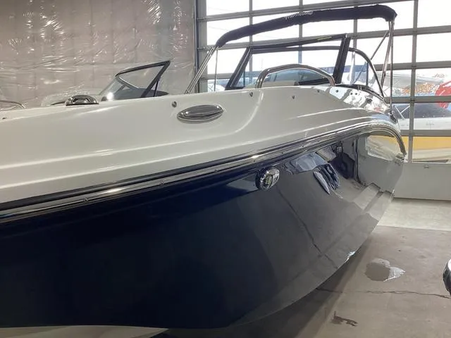 Slide: The Image of 2025 Hurricane SunDeck 217 OB boat in showroom, sleek design with navy and white finish. - 10