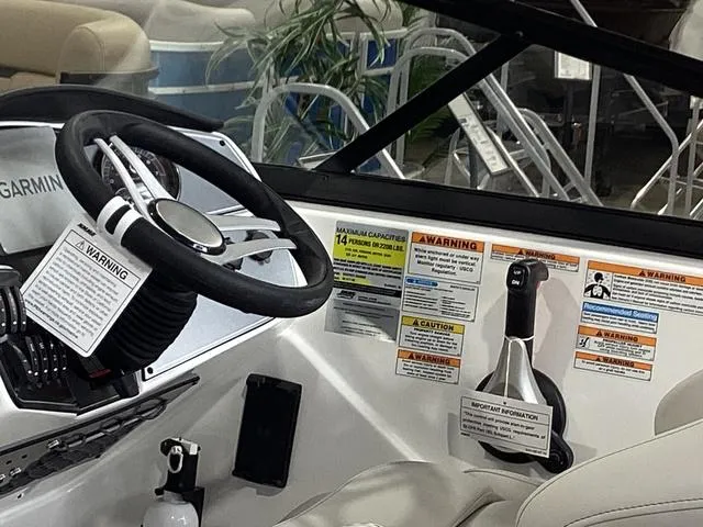 Slide: The Image of 2025 Hurricane SunDeck 217 OB boat dashboard with steering wheel and safety warnings. - 14