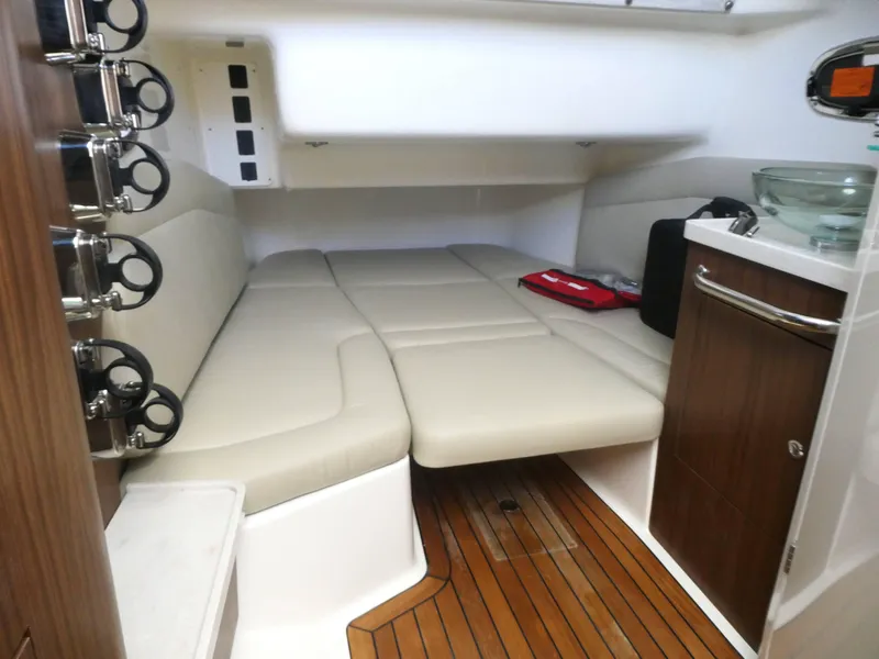 Slide: The Image of Interior of 2025 Boston Whaler 380 Outrage, featuring cushioned seating and wooden cabinetry. - 16