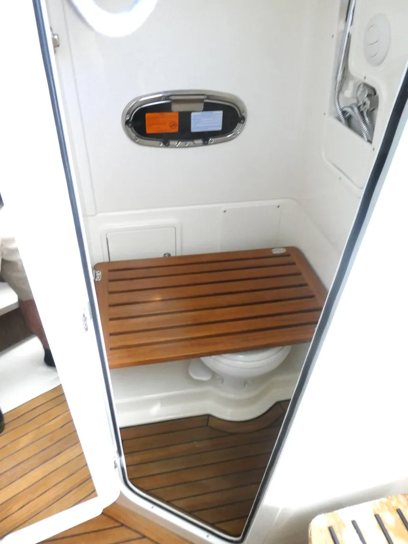 Slide: The Image of 2025 Boston Whaler 380 Outrage boat bathroom with wooden seat and flooring. - 20