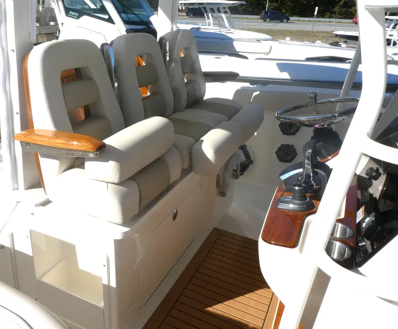 Slide: The Image of 2025 Boston Whaler 380 Outrage helm with cushioned seating and wooden accents. - 7