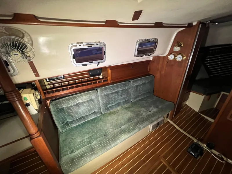 Slide: The Image of Interior of 1987 Bayfield 32C sailboat with green cushioned seating and wooden accents. - 26