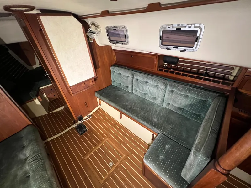 Slide: The Image of 1987 Bayfield 32C sailboat interior with wood paneling and green cushioned seating. - 29