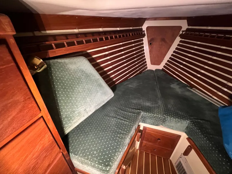 Slide: The Image of 1987 Bayfield 32C sailboat cabin with green cushions and wooden interior. - 32