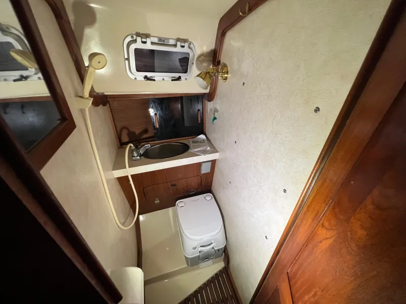Slide: The Image of 1987 Bayfield 32C sailboat bathroom with sink, toilet, and porthole window. - 34