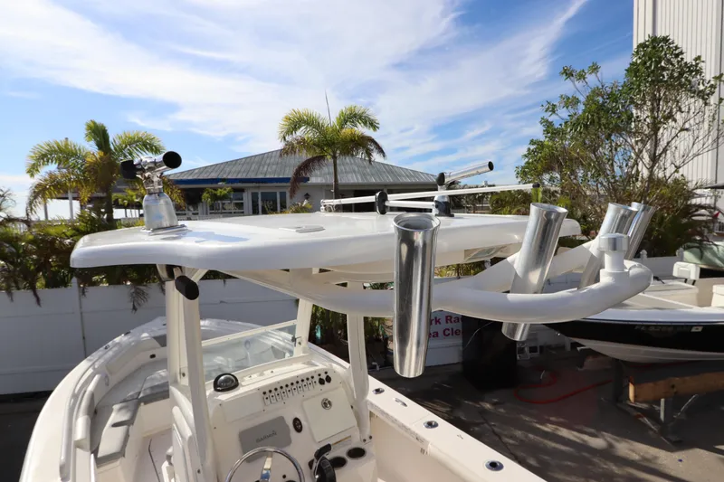Slide: The Image of 2012 Everglades 243 Center Console boat with rod holders, docked under a sunny sky. - 17
