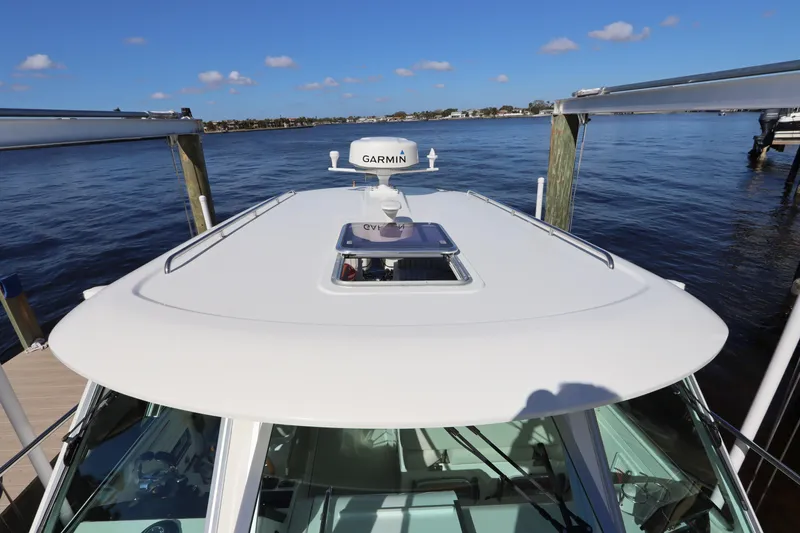 Slide: The Image of 2019 Back Cove 34O boat roof with Garmin radar, docked by the water. - 12