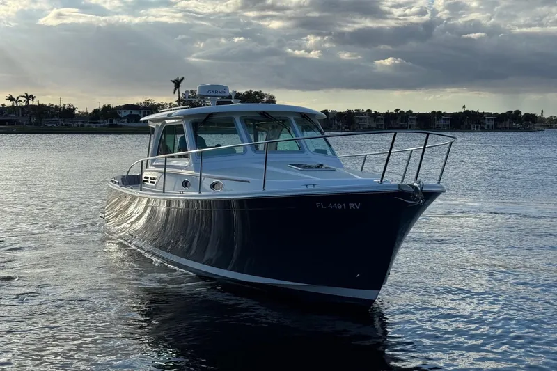 Slide: The Image of 2019 Back Cove 34O boat cruising on a calm waterway at sunset. - 4