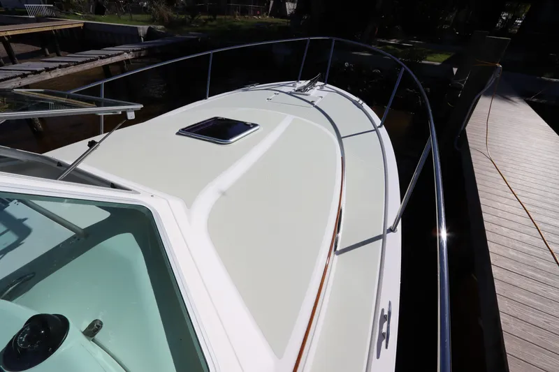 Slide: The Image of 2019 Back Cove 34O boat deck with railing and hatch, docked by wooden pier. - 9