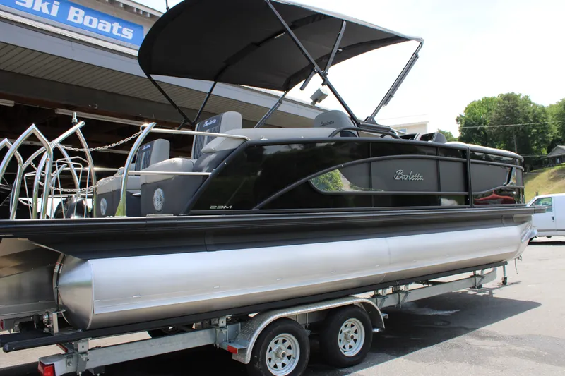 Slide: The Image of 2025 Barletta Lusso 23M pontoon boat on trailer, black exterior, under canopy. - 3