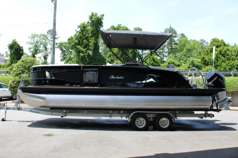 Slide: The Image of 2025 Barletta Lusso 23M pontoon boat on trailer, black exterior, parked outdoors. - 7