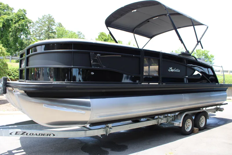 Slide: The Image of 2025 Barletta Lusso 23M pontoon boat on trailer with canopy, parked outdoors. - 8