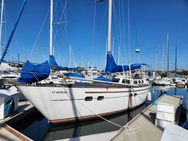 Slide: The Image of 1982 Custom King's Legend 41 sailboat docked in marina, blue sky background. - 45